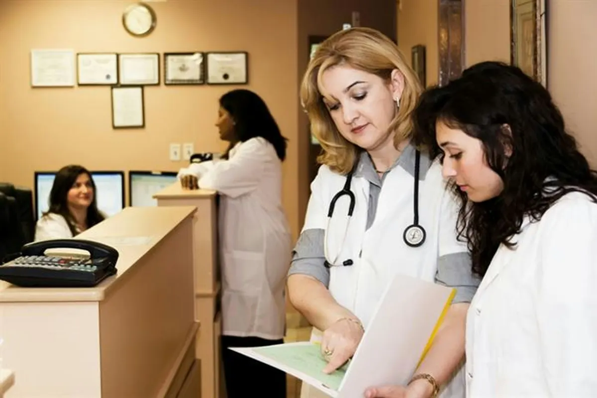 Clinic staff reviewing paperwork beside the front desk, with a receptionist on the phone behind them.